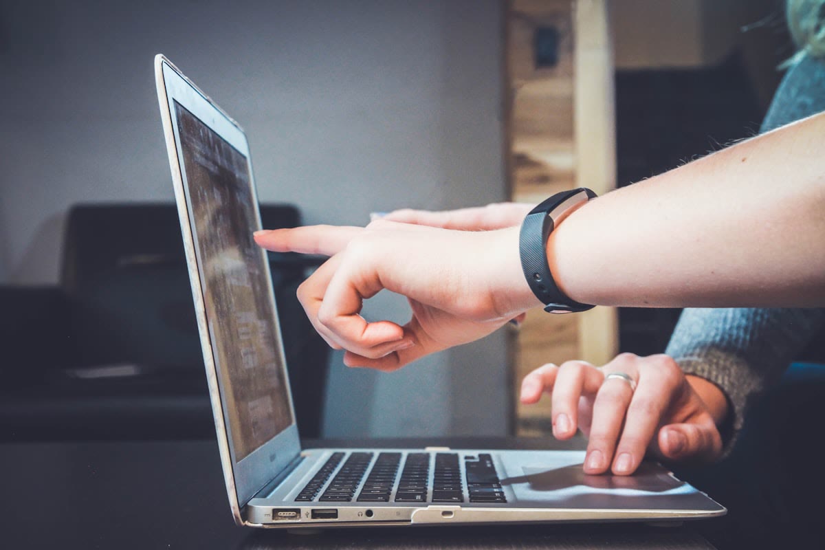 Colleagues pointing at a laptop while reviewing message wording before Meta submission
